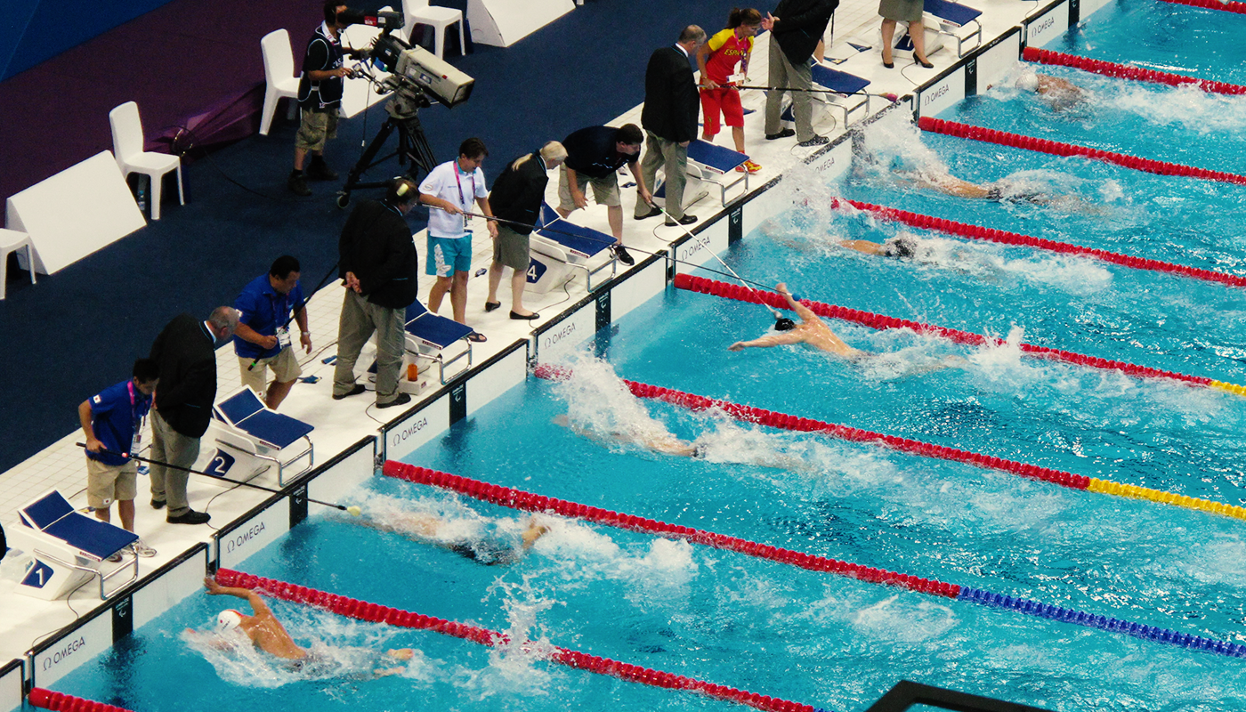 Paralympic swimmers swim in a lap pool and approach the wall.